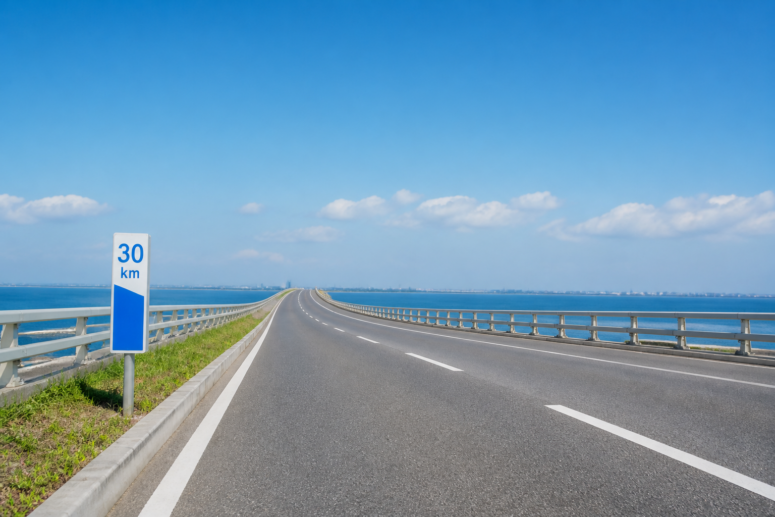 青空の下、緩やかな勾配が続く舗装道路と距離標識が写っている静物写真