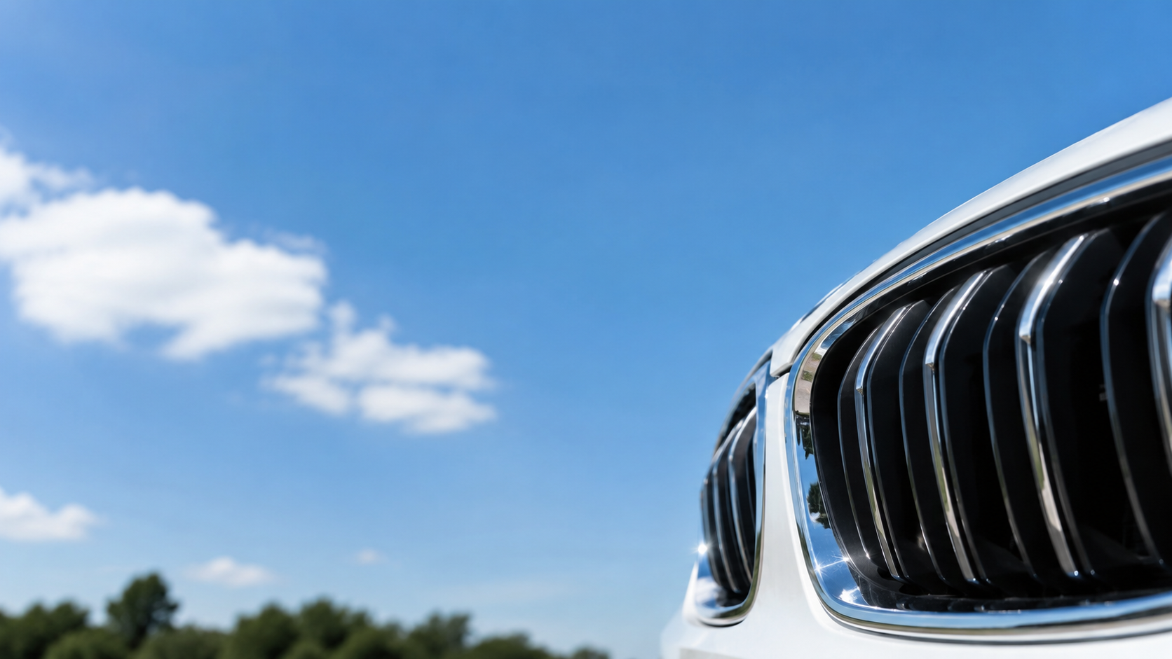 きれいに洗車された車のフロントグリルの一部と晴れた空